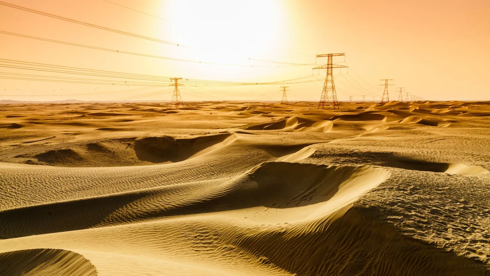 Golden desert landscape with sand dunes under a bright sun. Power lines stretch across the horizon, casting long shadows on the sand.