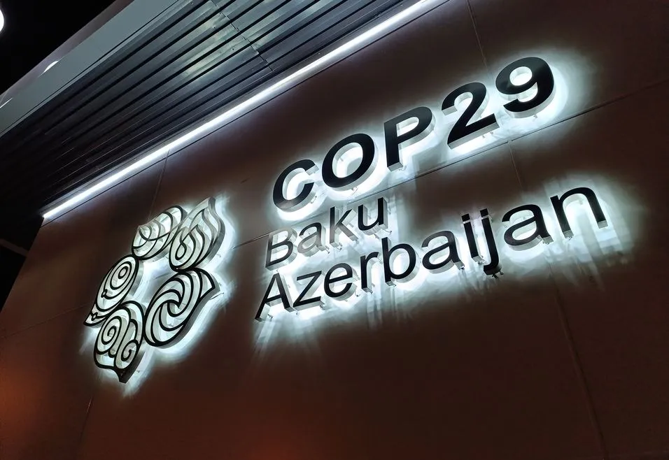 Illuminated sign for COP29 in Baku, Azerbaijan, featuring an artistic emblem and modern architectural elements.